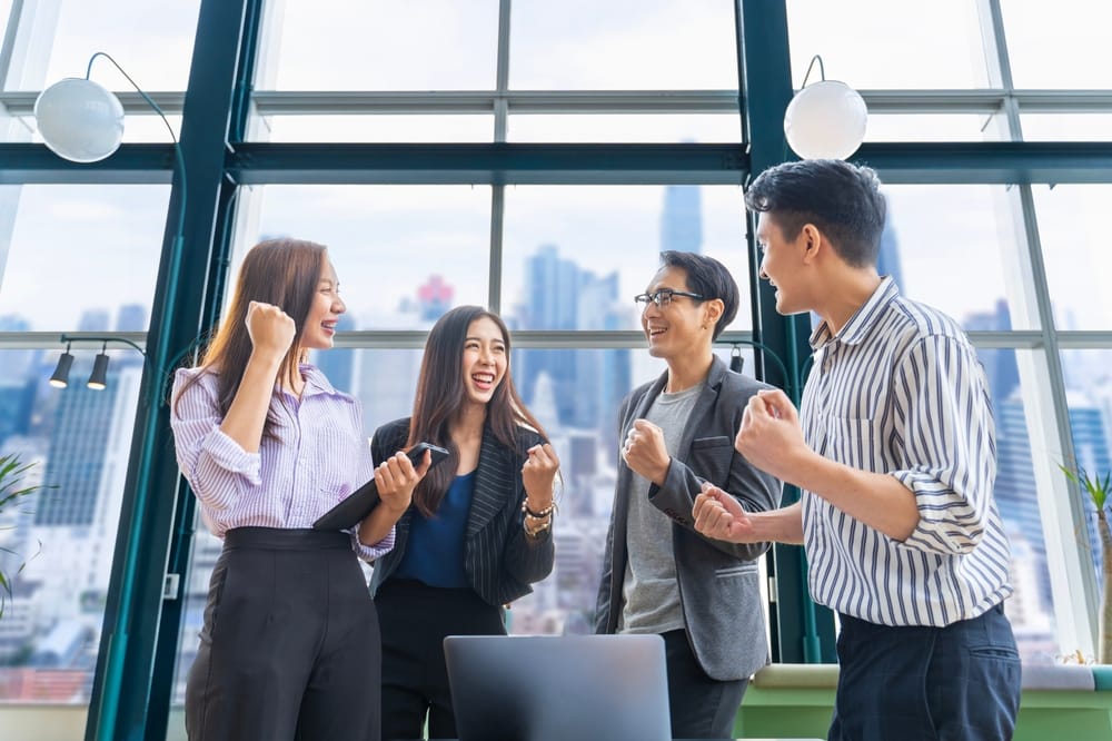 Group of happy Asian employees cheering together in an office, staff who receive the 1% payment with salary