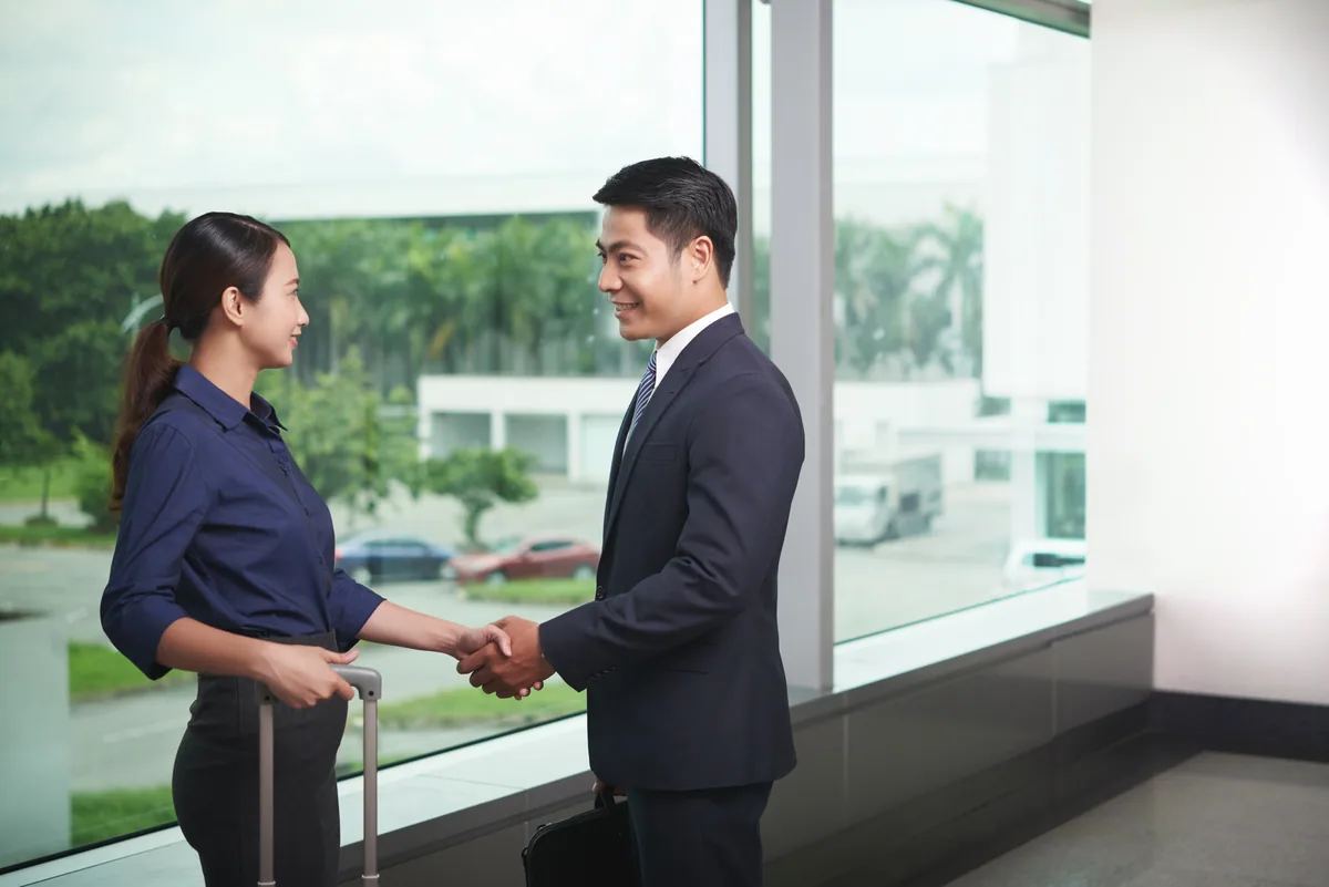 Two Asian professionals shaking hands in an office as a contract ends under the Law on Employment 2025