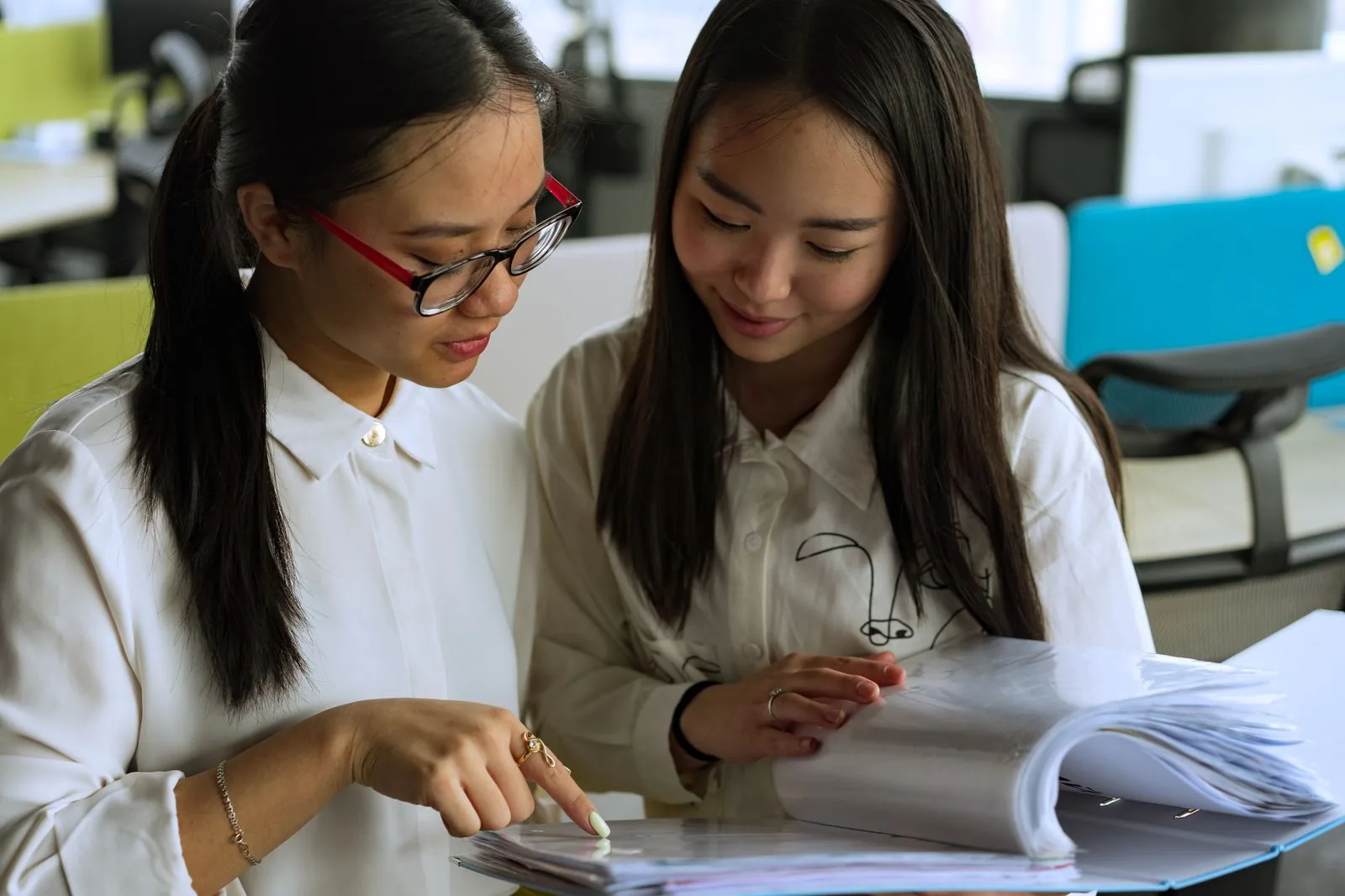 Two Vietnamese office staff checking a folder of salary and insurance records to confirm Social Insurance contributions
