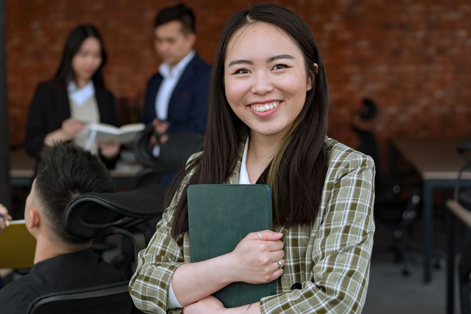Smiling Asian office employee holding documents on unemployment insurance for foreign workers